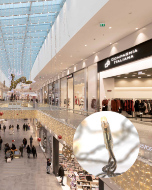 Indendørs shoppingcenter dekoreret med LED-lyskæder og en stor figur  i guldlys hængende fra loftet. Nærbillede af en LED-pære fra lyskæden, der bruges som belysning i udsmykningen.