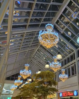 Shoppingcenter dekoreret med store, elegante lysekroner med LED-lys, der hænger fra glastaget og skaber en luksuriøs og festlig atmosfære under juletiden.