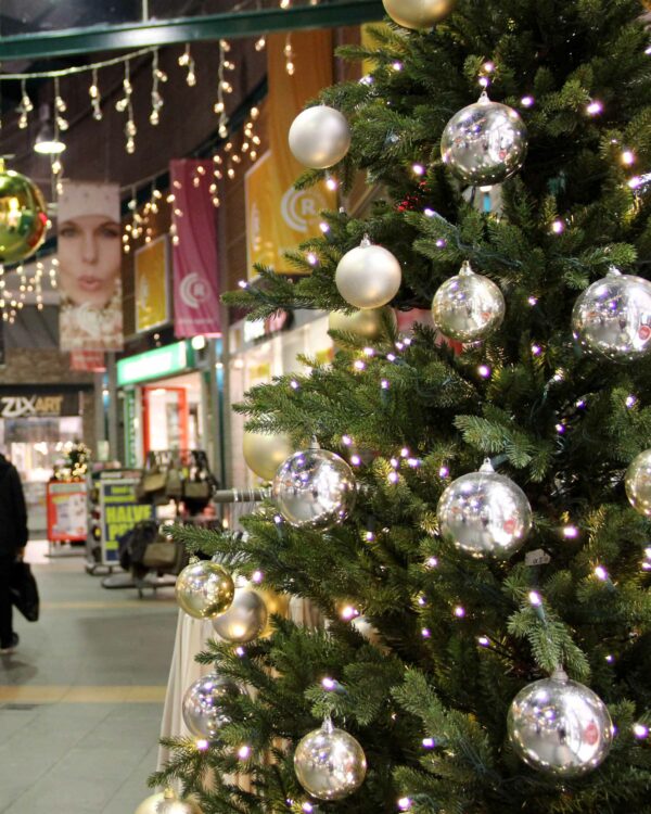 Shoppingcenter med pyntet juletræ med julekugler og lyskæder.