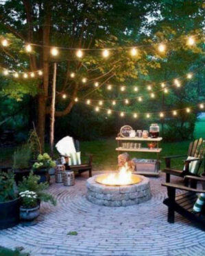 Stemningsfuldt terrassemiljø med varm hvide festoon-lyskæder over bålsted og loungemøbler. Perfekt til hyggelige sommeraftener i haven, på terrassen eller ved events.