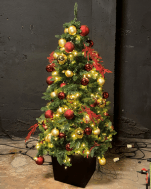 Færdigpyntet juletræ med røde og gyldne kugler samt varm hvide LED-lys. Skaber en klassisk, hyggelig og elegant julestemning til indendørs dekoration.