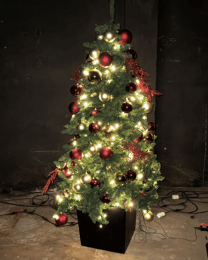Oplyst juletræ pyntet med røde og gyldne kugler samt varm hvide LED-lys. Giver et klassisk og stemningsfuldt udtryk i mørke omgivelser.