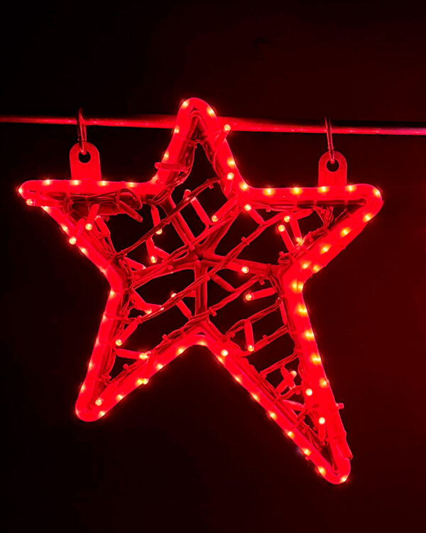 Nærbillede af rødt LED-stjernemotiv ophængt på wire mod sort baggrund, hvor de klare lys fremhæver form, detaljer og velegnethed til professionel juleudsmykning og facadeinstallationer.
