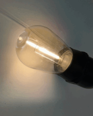 Klar E27 LED-pære med varm hvid filament, monteret i sort fatning, velegnet til party-lyskæder og stemningsfuld indendørs eller udendørs belysning.